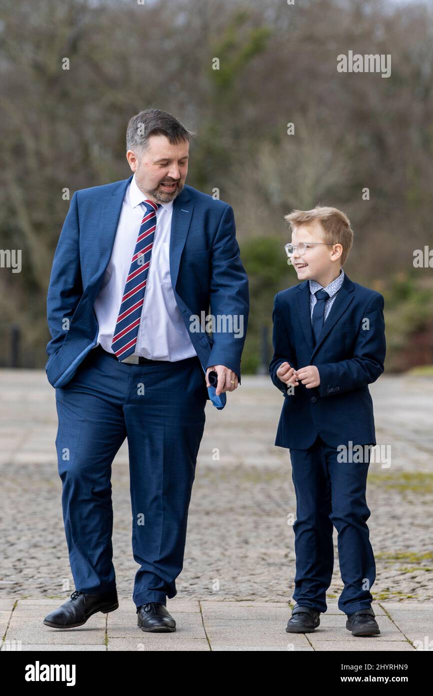 NI Ministro della Sanità Robin Swann con Mack Brownlee (8 anni) sui gradini degli edifici del Parlamento a Stormont a Belfast. Data foto: Martedì 15 marzo 2022. Foto Stock