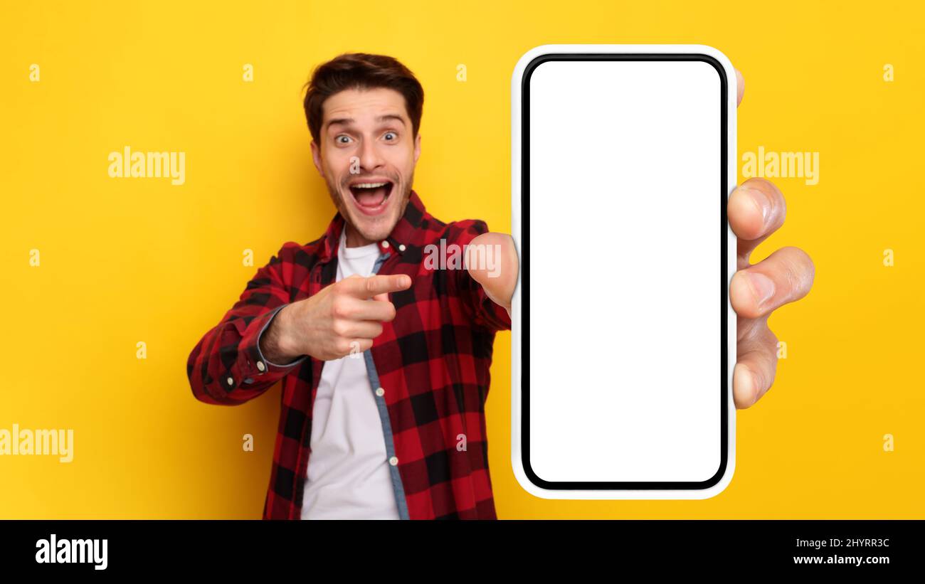 Un ragazzo scioccato che punta allo schermo bianco vuoto dello smartphone Foto Stock