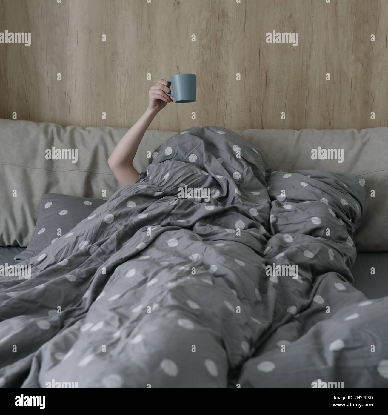 mattina, intimità, concetto di casa accogliente - una mano con una tazza di caffè o tè a letto a casa Foto Stock