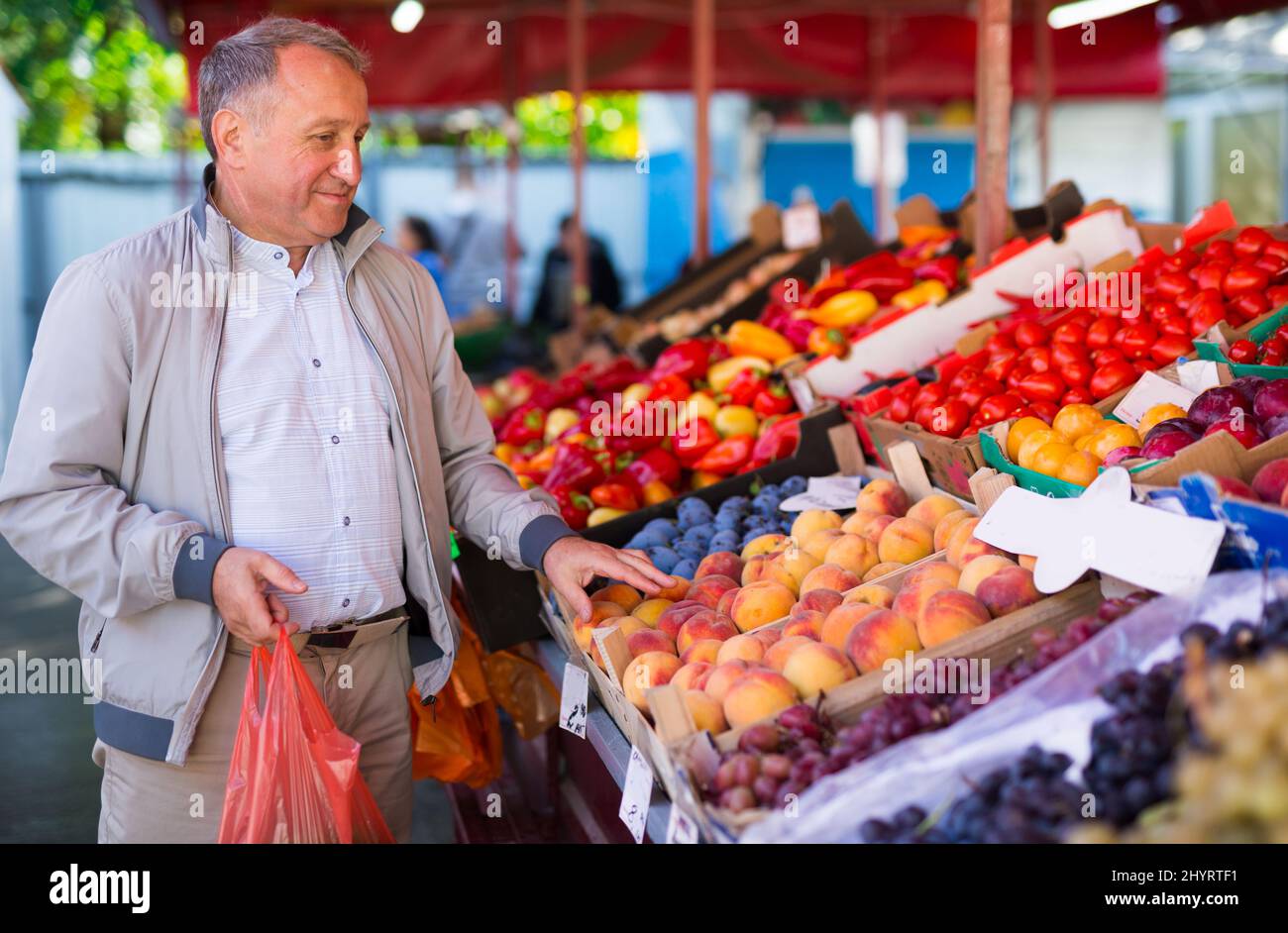 Uomo di mezza età che acquista pesche Foto Stock