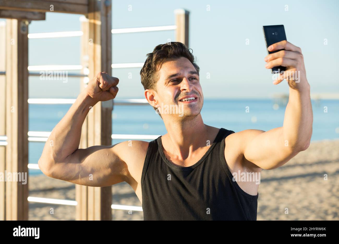 Uomo allegro mostrando bicipiti prendendo selfie Foto Stock