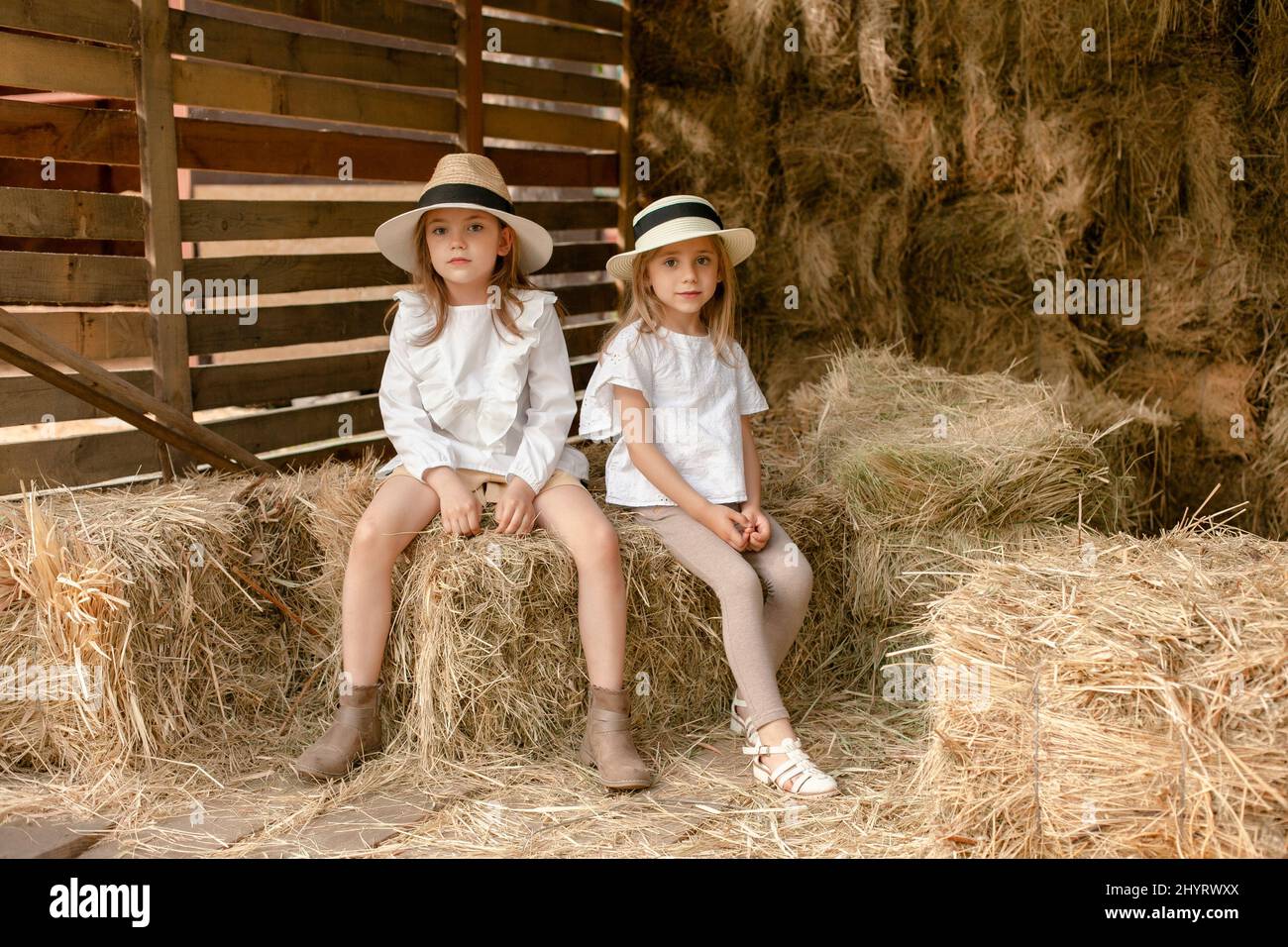 Due bambine in stile country vestiti seduti in fienile il giorno d estate Foto stock Alamy