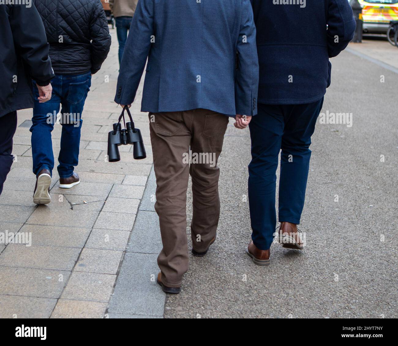 Cheltenham, Regno Unito. 15th Mar 2022. Un gruppo di uomini cammina verso un bus navetta per le gare di Cheltenham, con un paio di binoculari in mano. Cheltenham, 15.03.2022, Marcin Riehs/ Pathos Credit: Pathos Images/Alamy Live News Foto Stock