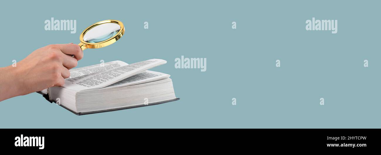 Banner con mano che tiene la lente d'ingrandimento sopra il libro. Analisi delle informazioni, ricerca dei dati, concetto educativo. CopySpace. Foto di alta qualità Foto Stock