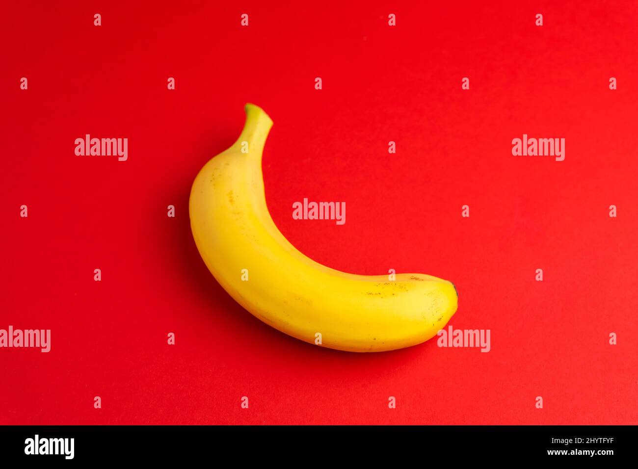 Banana gialla su sfondo rosso isolato. Cibo sano. Concetto di dieta di frutta fresca tropicale Foto Stock