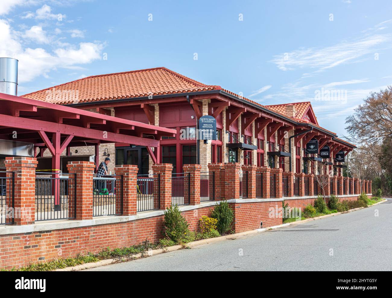 BELMONT, NC, USA-8 MARZO 2022: Vecchio deposito ferroviario, chiamato North Main Station, convertito in negozi e ristoranti. Un uomo lavora al ristorante all'aperto per il Foto Stock