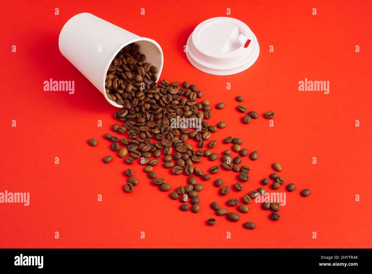 Tazza da caffè di carta bianca da asporto con tappo su sfondo rosso e chicchi tostati Foto Stock