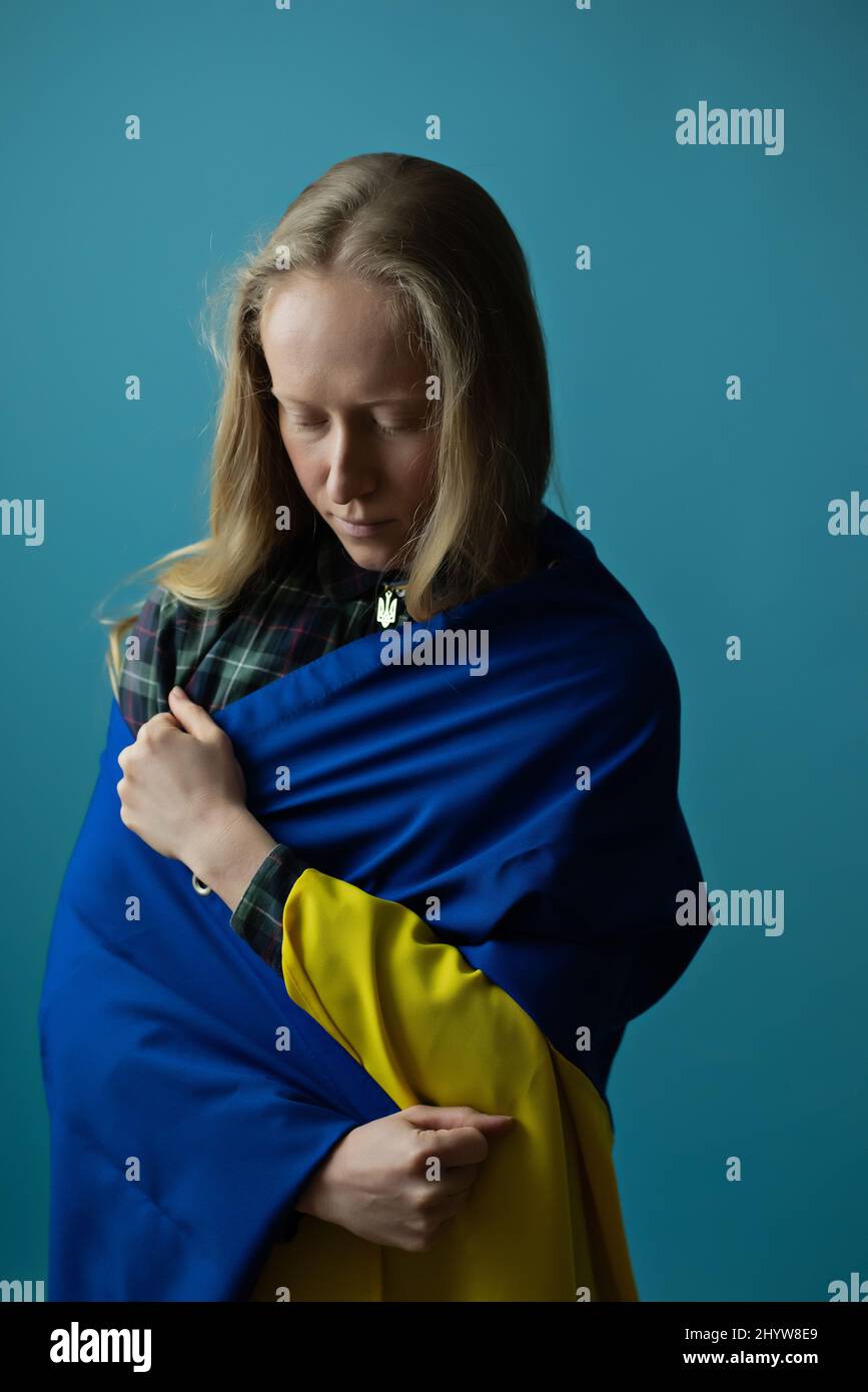 Una vera donna bionda Ucraina durante la guerra con la bandiera Ucraina gialla e blu sulla sua testa. La Russia ha attaccato l'Ucraina il 24 febbraio 2022. Foto Stock