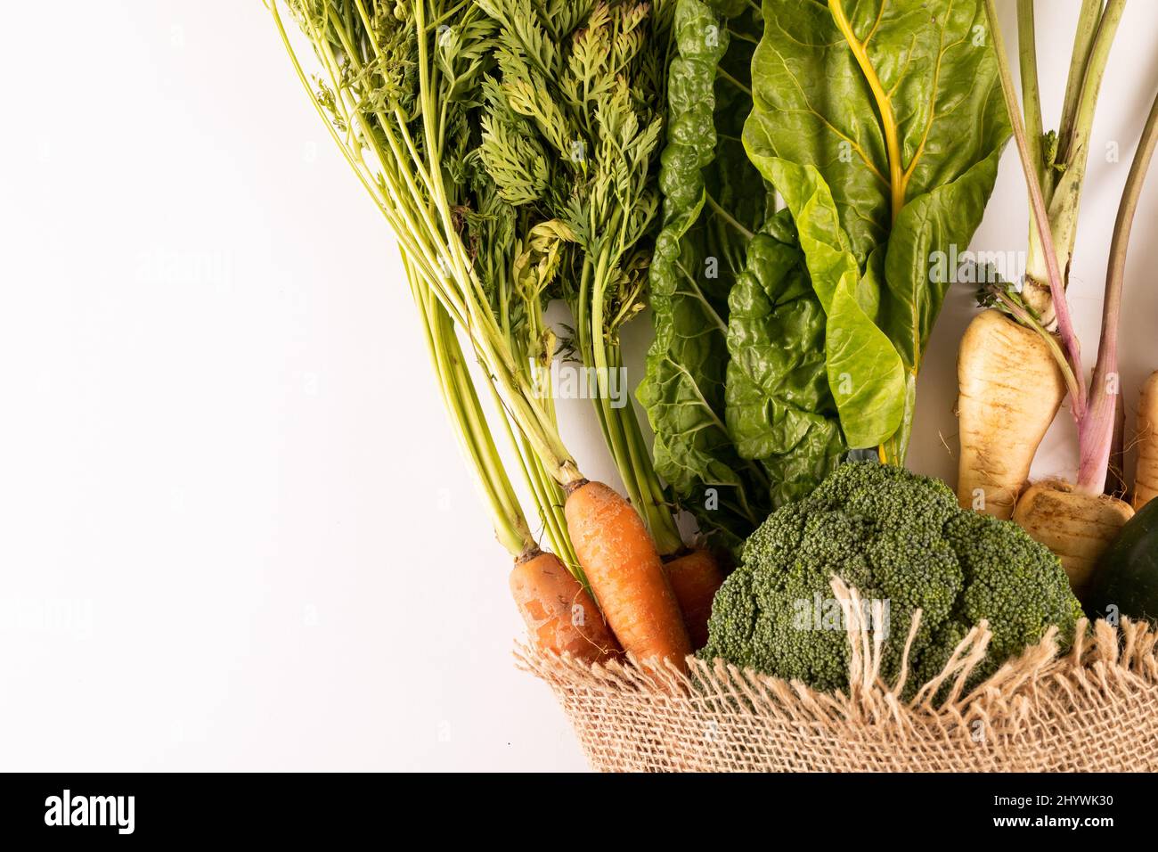 Vista dall'alto di verdure fresche organiche con burlap su sfondo bianco, spazio copia Foto Stock