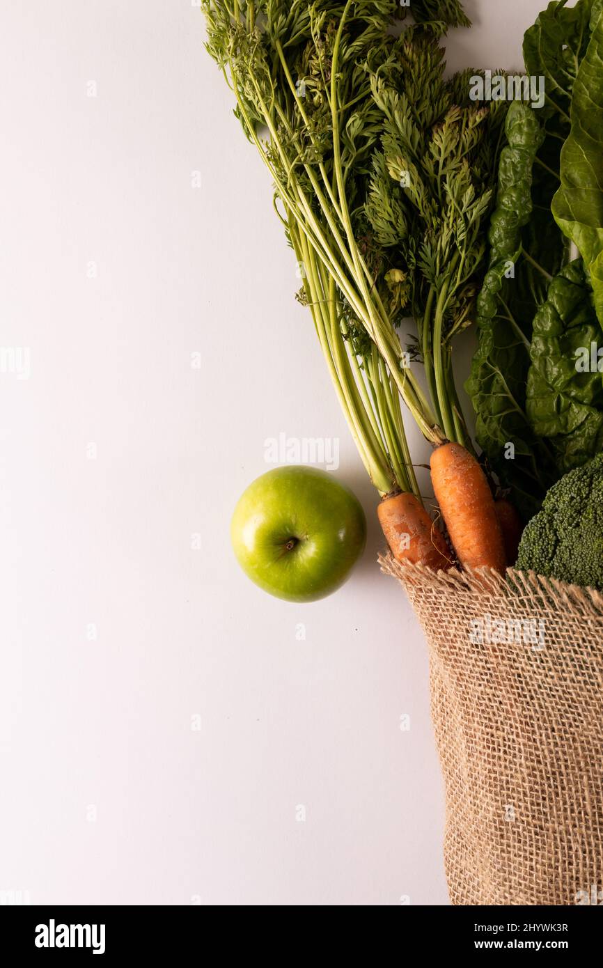 Vista dall'alto di verdure fresche e frutta con burlap su sfondo bianco, spazio copia Foto Stock