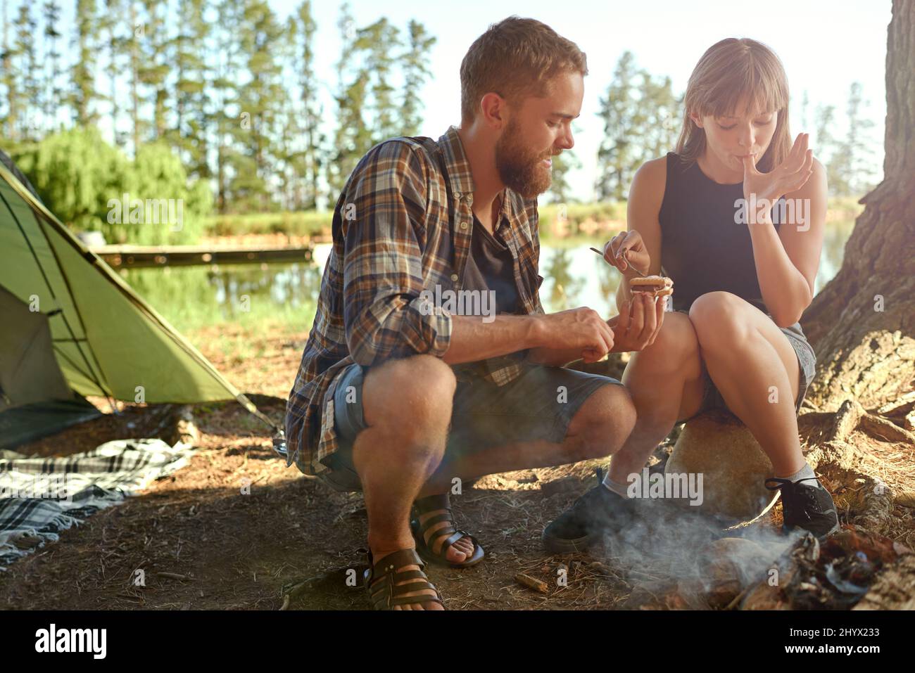 Nei boschi. Scatto di una giovane coppia che fa smores durante il campeggio. Foto Stock