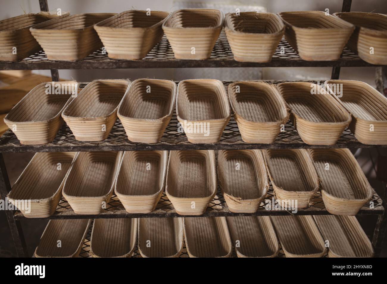 Shot a telaio pieno di cesti di pane in vimini disposti affiancati sullo scaffale in panetteria Foto Stock