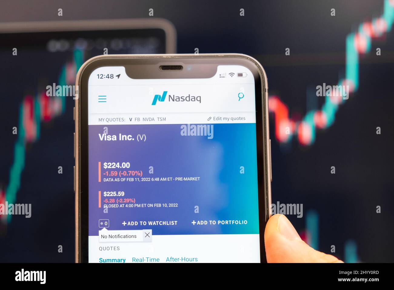 Visto logo del prezzo di stock sullo schermo di smartphone in mano mans con cambiamento di tendenza sul grafico sullo sfondo, Febbraio 2022, San Francisco, USA. Foto Stock