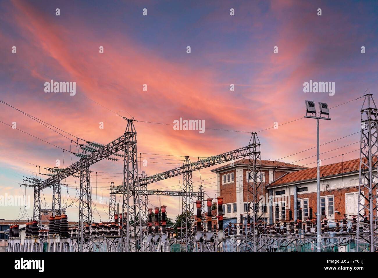 Trasformatore elettrico con piloni con cavi ad alta tensione, cielo colorato al tramonto, costoso concetto di costo energetico Foto Stock