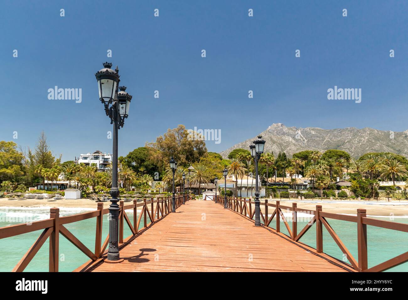 Vista sul ponte in legno rosso 'Embarcadero' a Marbella. Vista della zona di lusso Puente Romano, urbanizzazioni costose. Montagna 'la Concha'. Foto Stock