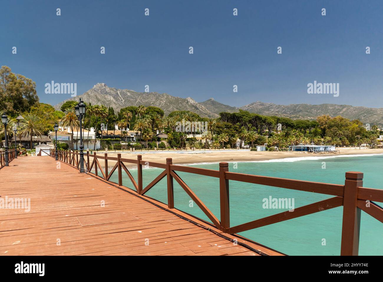 Vista sul ponte in legno rosso 'Embarcadero' a Marbella. Vista della zona di lusso Puente Romano, urbanizzazioni costose. Montagna 'la Concha'. Foto Stock