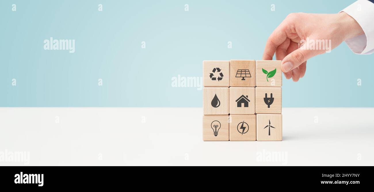 Tutela dell'ambiente, fonti energetiche rinnovabili e sostenibili. Mano fissa blocchi con simboli di energia rinnovabile Foto Stock