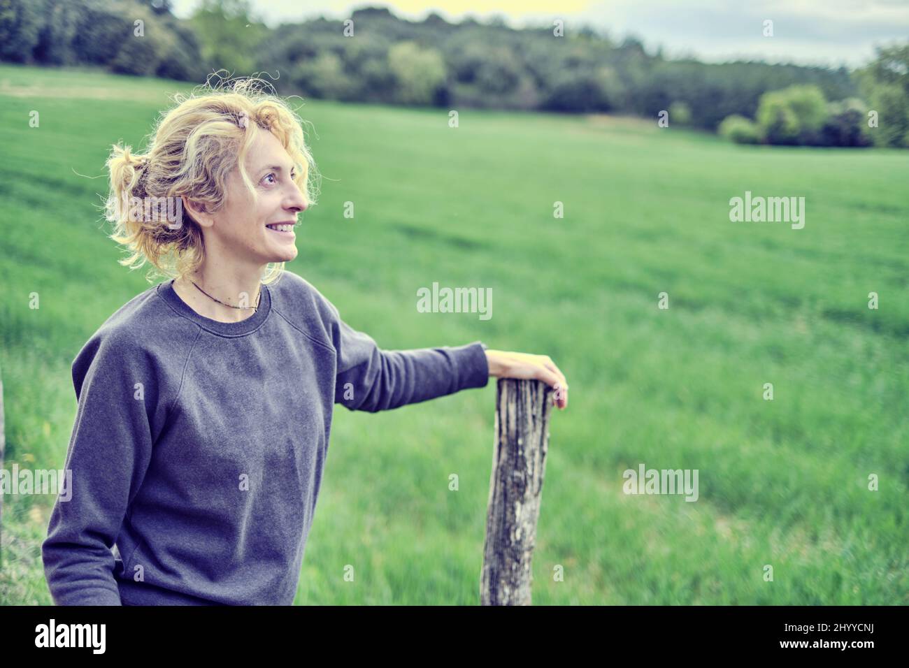 Ritratto di una giovane donna caucasica matura in piedi all'aperto appoggiata su un palo da sentiero in primavera. Navarra, Spagna, Europa. Foto Stock