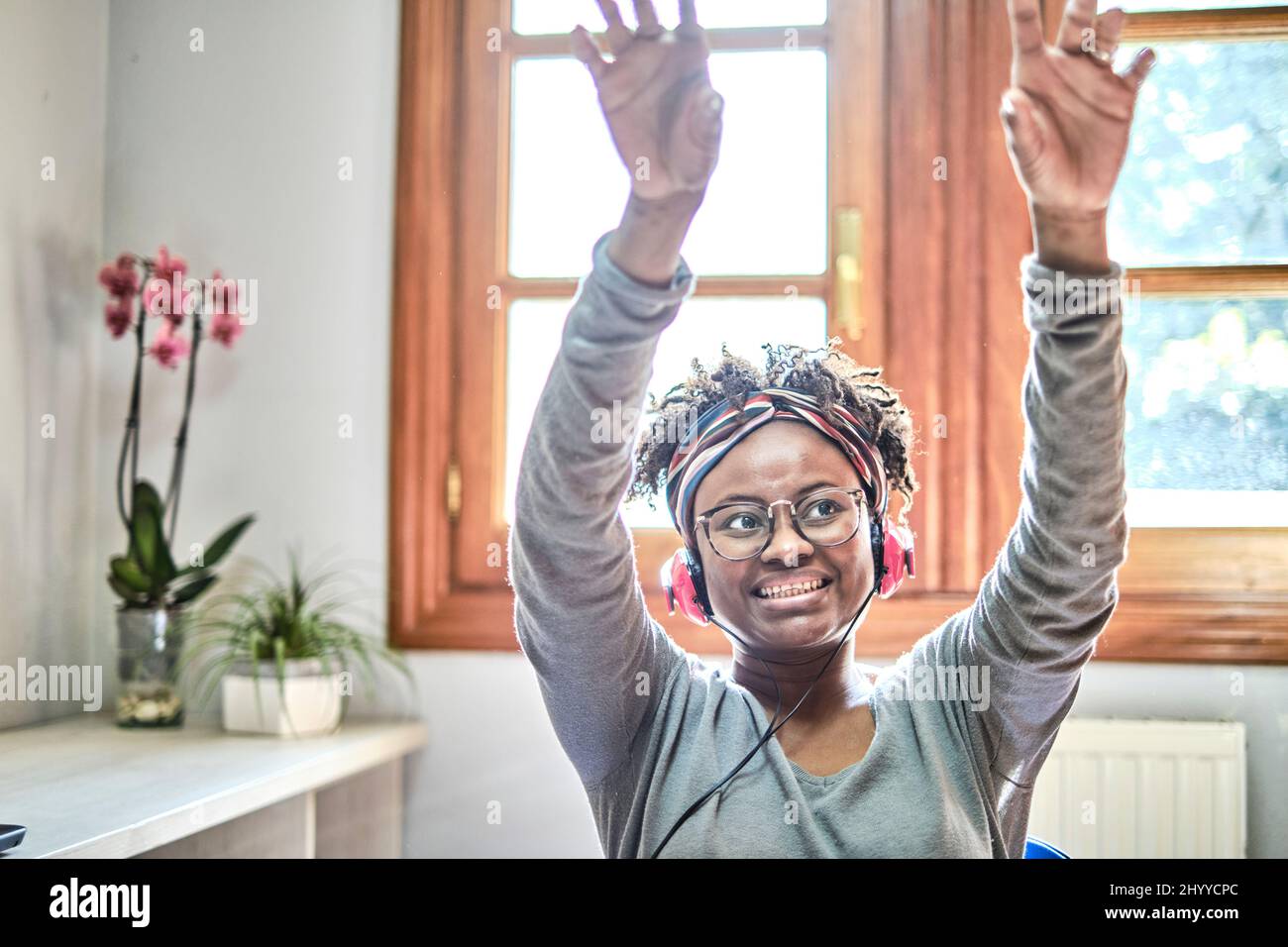 Giovane donna nera con acconciatura afro che ascolta la musica con le cuffie in casa. Concetto di stile di vita. Foto Stock