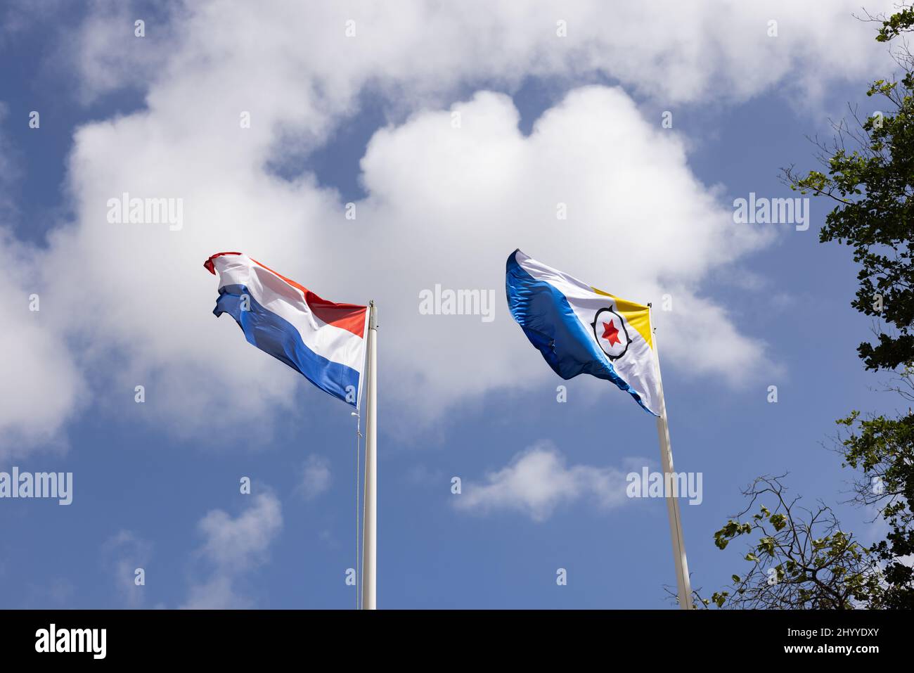 Bandiera di Bonaire e Paesi Bassi che volano nel vento su sfondo cielo blu. Foto Stock