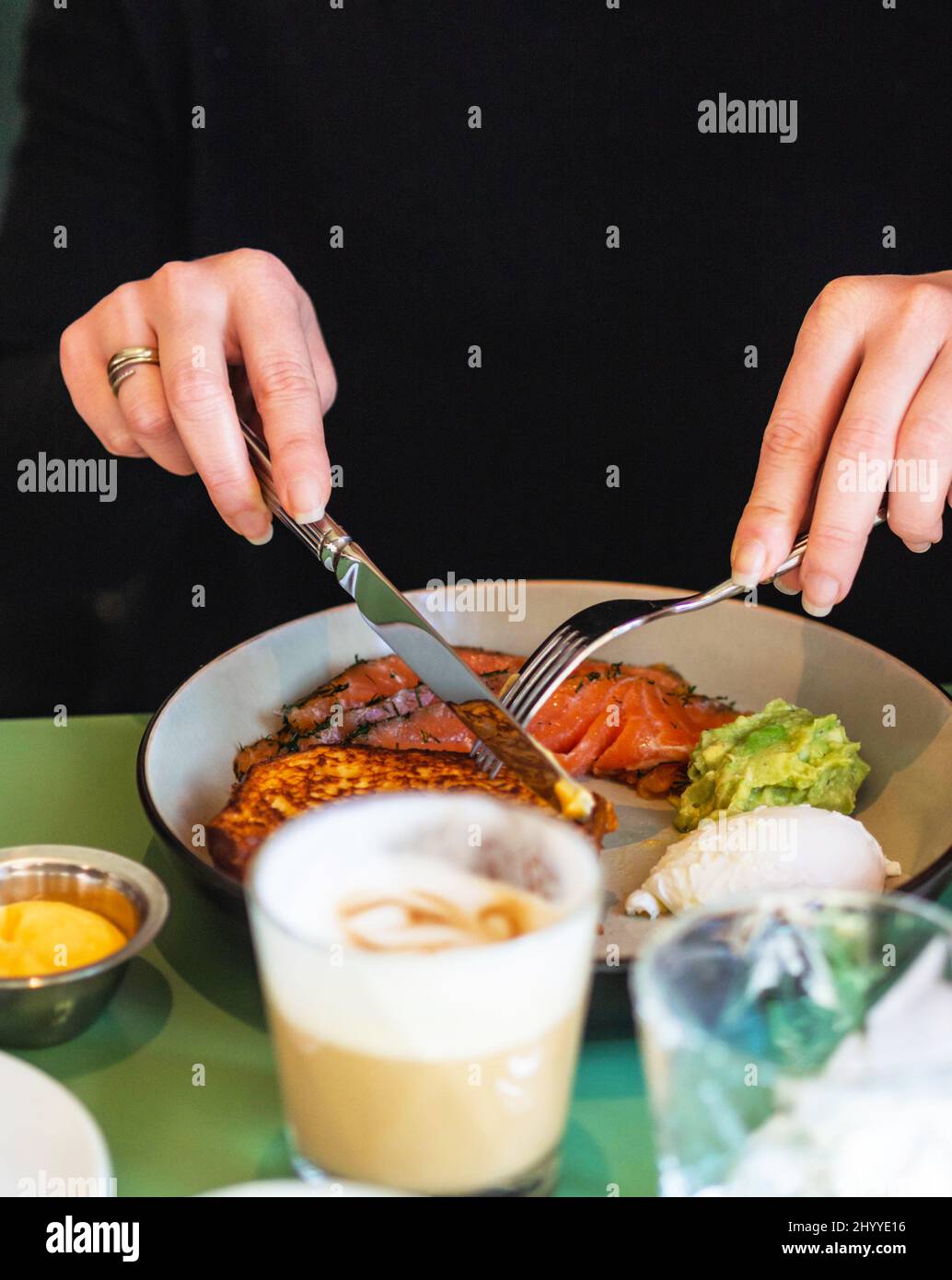 Primo piano su una giovane donna con le mani in mano come ella è avere la prima colazione Foto Stock