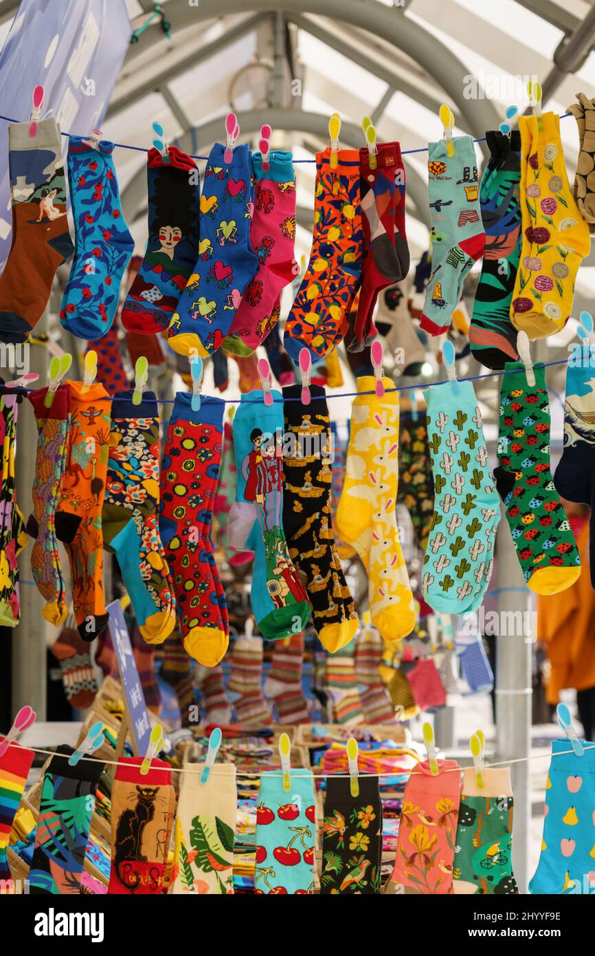 Una vivace e abbondante mostra di calzini colorati alla moda appesi su pioli a Street Market, York, North Yorkshire, Inghilterra, Regno Unito. Foto Stock