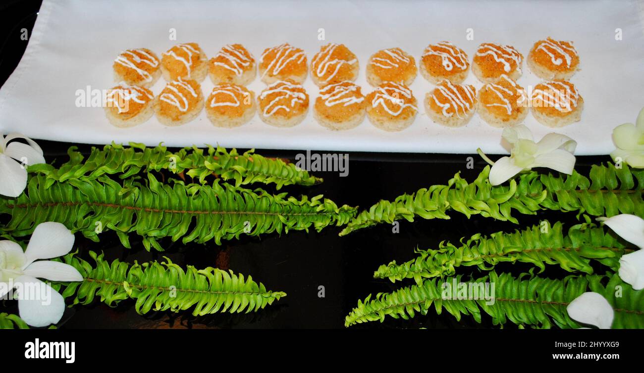 Brinda con caviale dorato e crema acida cocktail hors d'oeuvre su vassoio decorato con felci e orchidee bianche Foto Stock