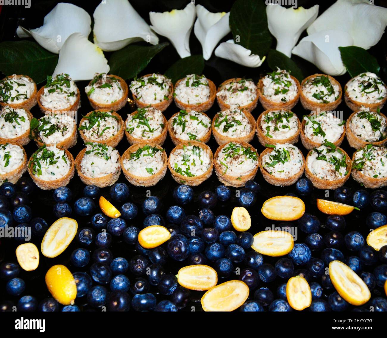 Insalata di pollo con dragoncello in piccole coppette da cocktail su vassoio decorato con mirtilli, kumquat e petali di rosa bianca Foto Stock