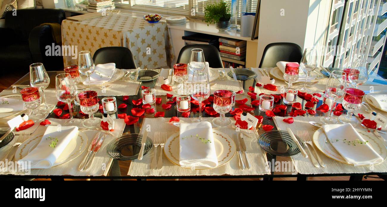 Tavolo da pranzo decorato con petali di rosa e candele votive Iittala in attesa di cena ospiti. Foto Stock
