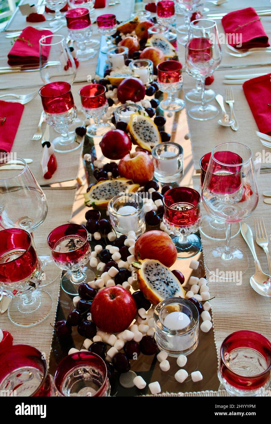 Tavolo da pranzo decorato con mele, frutta del drago, marshmallows e portacandele votive finlandesi Marimekko Kivi in attesa di cena ospiti. Foto Stock