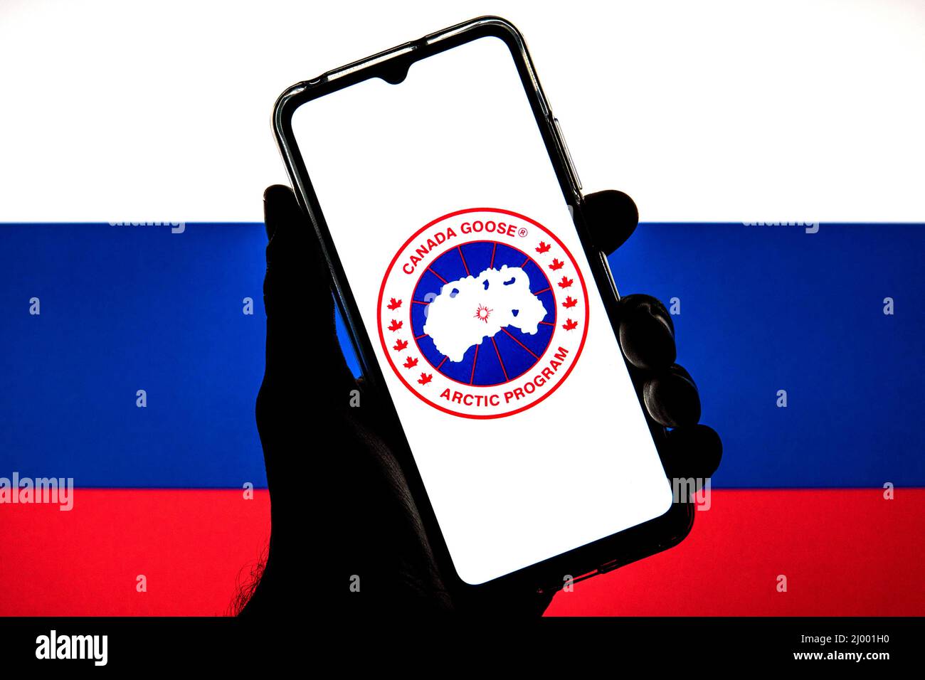 In questa illustrazione della foto viene visualizzato un logo Canada Goose su uno smartphone con una bandiera della Russia sullo sfondo. Foto Stock