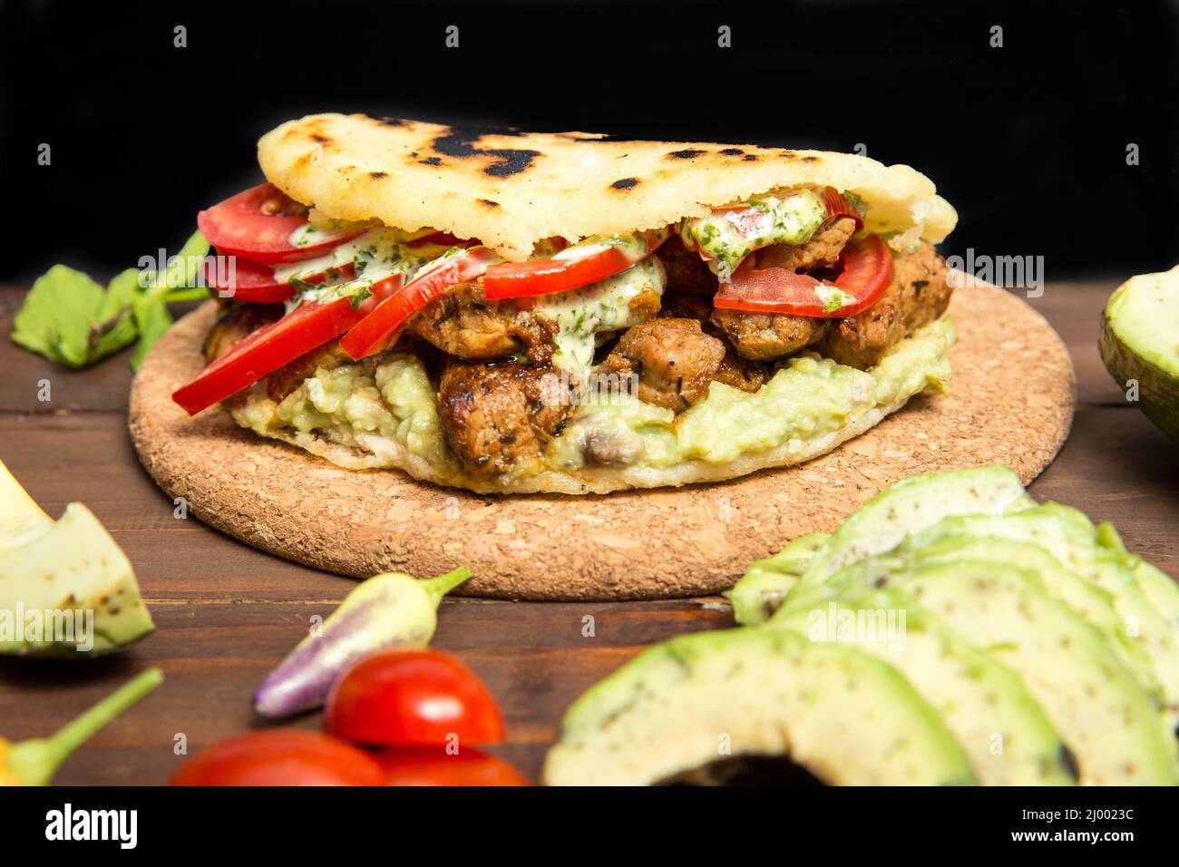 Arepas - tradizionale cibo colombiano originario dell'America Latina disposto su una vecchia tavola rustica in legno mescolato con carne, verdura e avocado Foto Stock