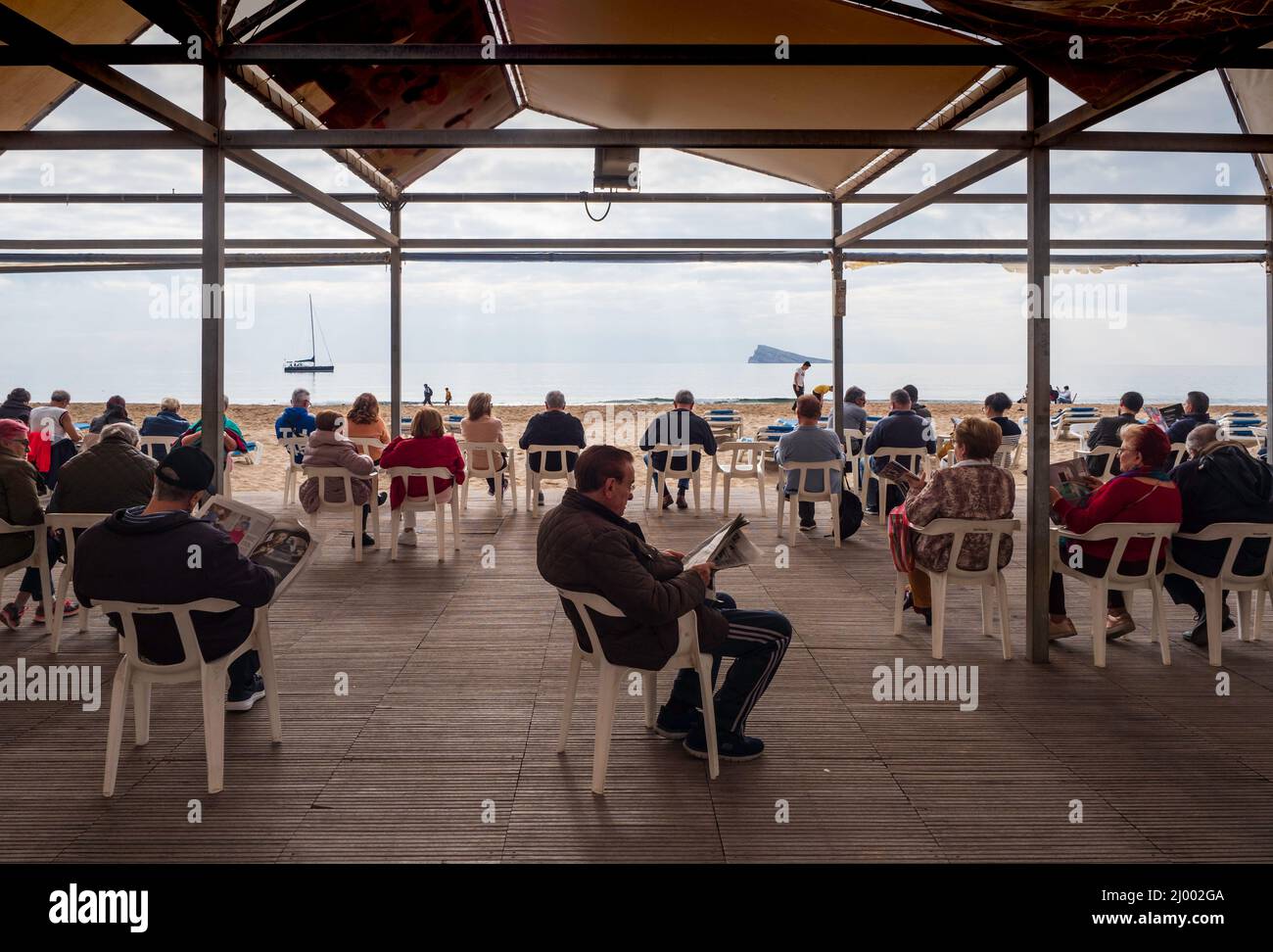 Gruppo di pensionati seduti sotto una tenda di fronte al mare a Benidorm Foto Stock