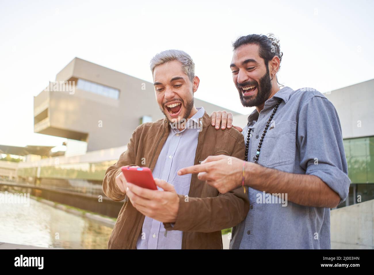 Ritratto di una coppia gay sorpresa guardando qualcosa nel loro telefono cellulare. Foto Stock