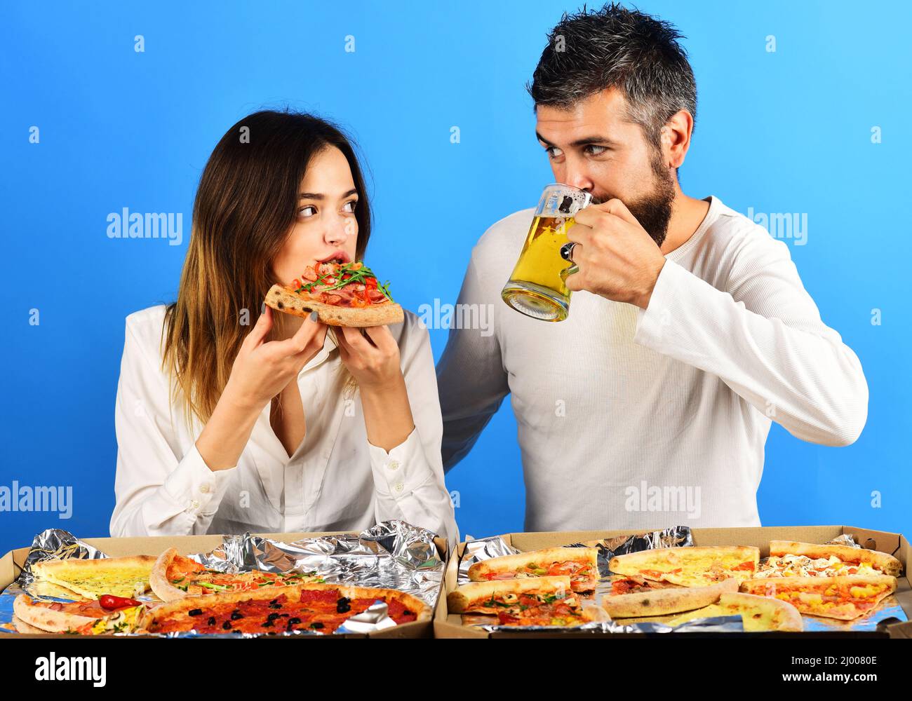 Coppia amorevole in abiti casual mangiare pizza. Uomo che beve birra, donna che mangia pizza a fette. Fast food. Foto Stock