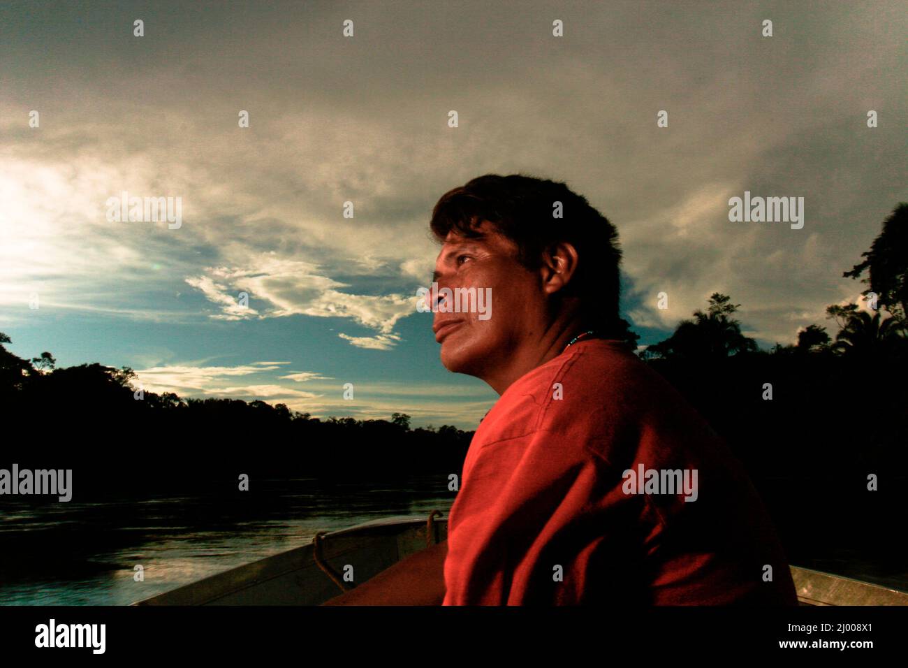 Ritratto di una guida Yanomami al tramonto sul fiume Putaco. Gli Yanomami sono un antico popolo indigeno che vive lungo il confine tra Brasile e Venezuela nelle fertili terre dei fiumi Orinoco e Amazzonia. Sono semi nomadi e pesantemente dipendenti dalla natura sia per la caccia che per l'agricoltura. Ma oggi, la sopravvivenza fisica e culturale del popolo Yanomami è stata minacciata dalle miniere d'oro, dalla deforestazione e dalle malattie. Alto Stato di Orinoco, Venezuela. Luglio 23, 2007. Parte della storia fotografica, 'Yanomamis: Lo Spirito di Amazonia', di Diego Martinez. Foto Stock