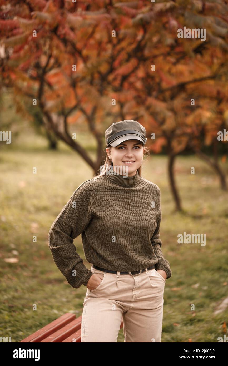 Bella donna bionda Ucraina in un maglione verde lavorato a maglia e jeans  leggeri in un parco autunnale con alberi d'arancio. Autunno d'oro Foto  stock - Alamy