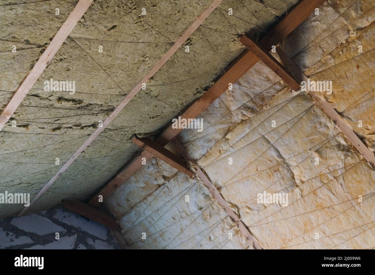 Il tetto è isolato con lana di vetro di diversa densità. Tecnologia di isolamento del tetto. Lana minerale che posa tra le travi Foto Stock