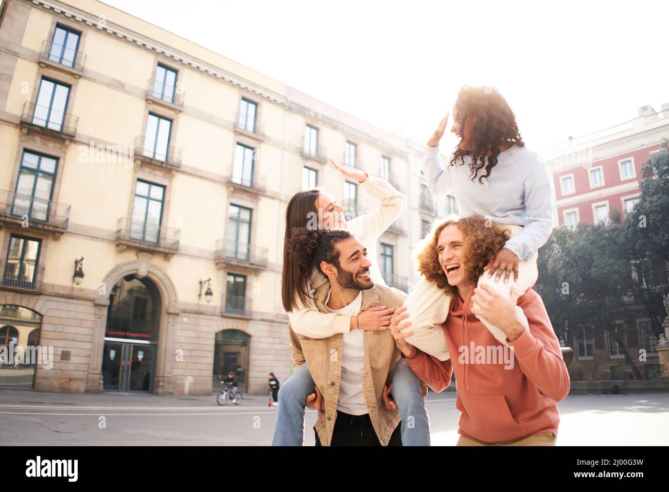 Due belle coppie europee in piggyback ridando e divertirsi. Concetto di amicizia Foto Stock