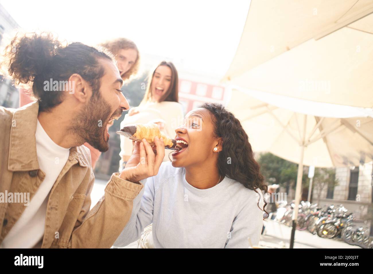 Scena romantica di una coppia che condivide un pasto il loro primo giorno, mentre gli amici guardare sullo sfondo Foto Stock