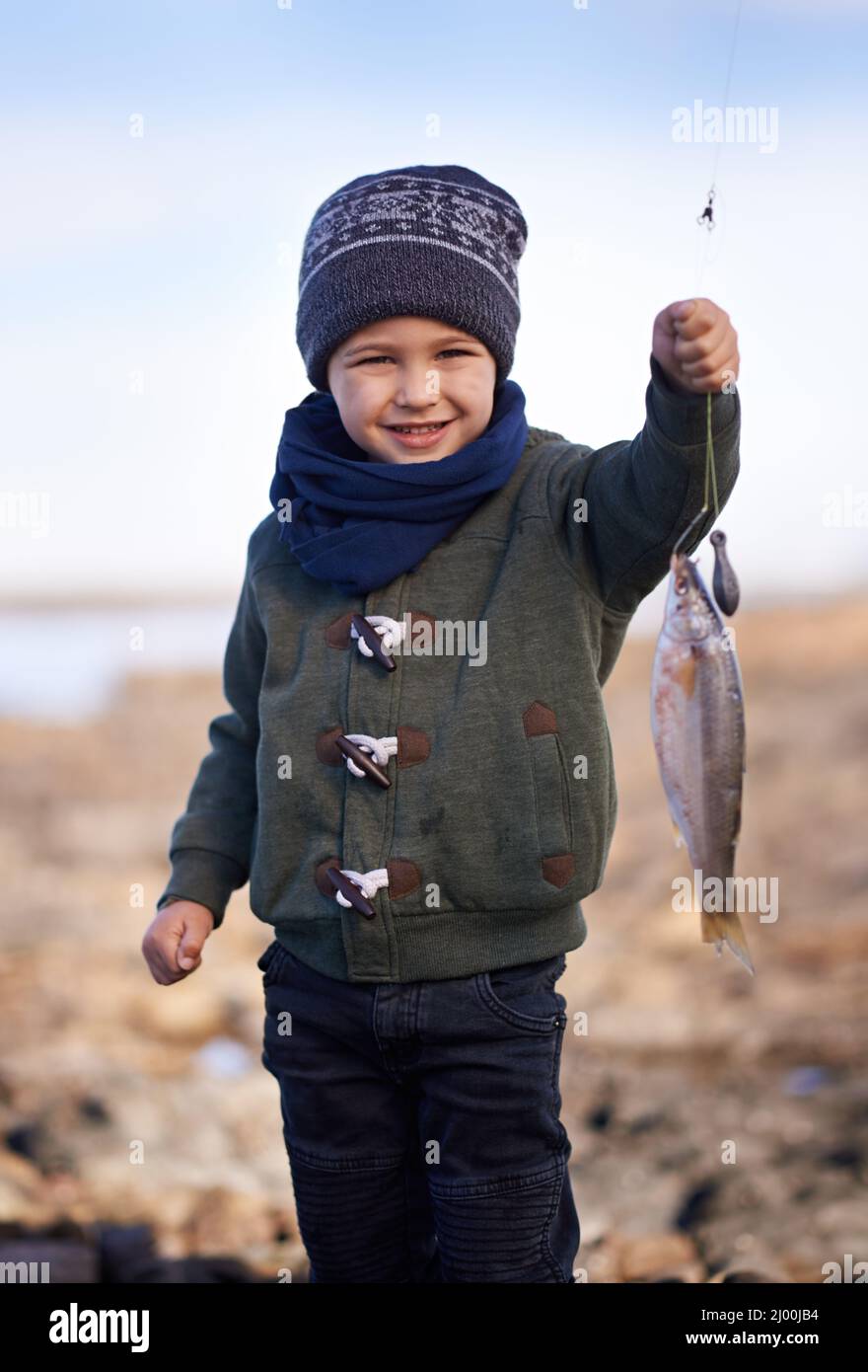 Guarda, il suo più grande cattura ancora. Ritratto di un ragazzino carino che tiene il pesce che ha catturato. Foto Stock