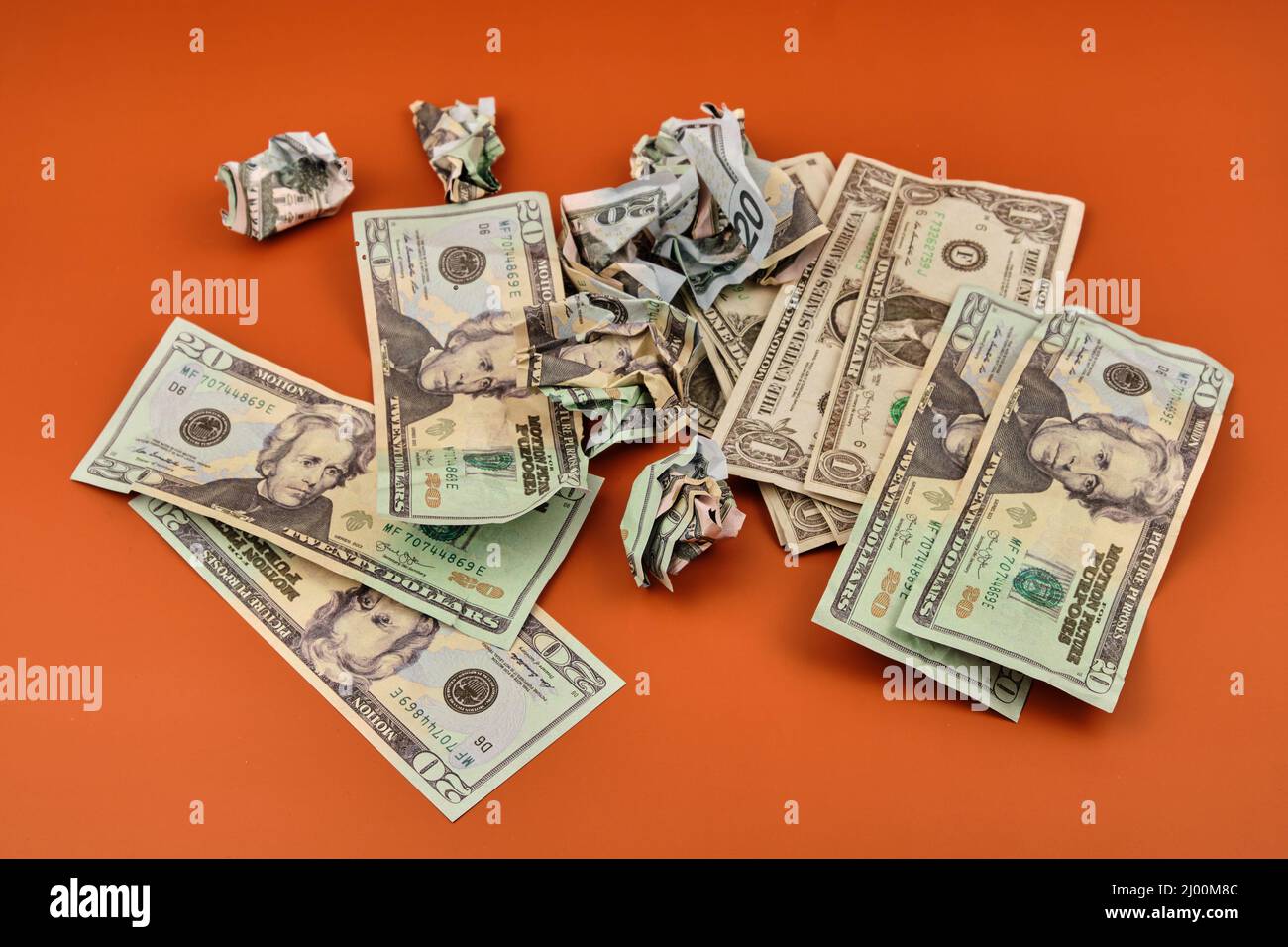 Un mucchio di dollari sbriciolati e sporchi che giacciono su un tavolo arancione. Concetto di denaro sporco. Foto Stock