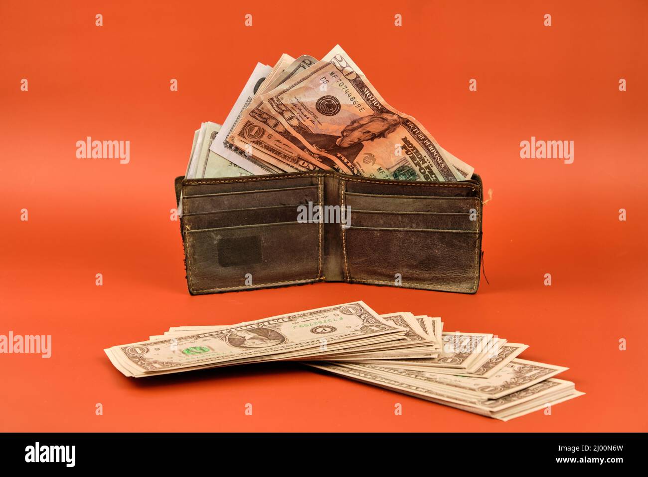 Portafoglio in pelle pieno di banconote in denaro su sfondo arancione. Concetto dell'importanza del risparmio. Foto Stock