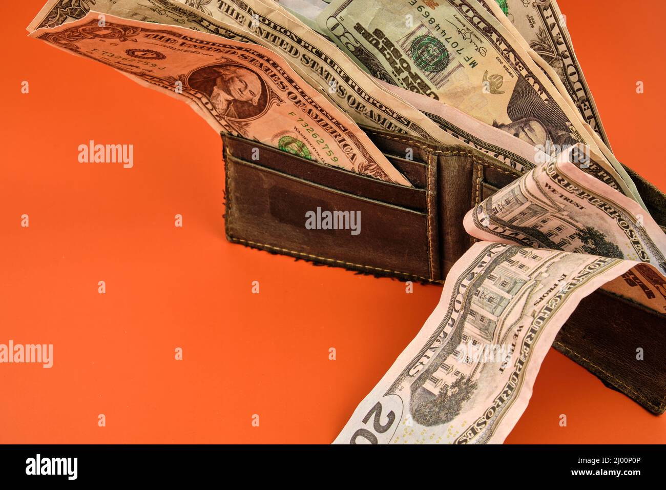 Portafoglio in pelle pieno di banconote in denaro su sfondo arancione. Concetto dell'importanza del risparmio. Foto Stock