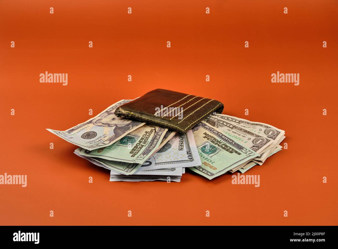 Portafoglio in pelle pieno di banconote in denaro su sfondo arancione. Concetto dell'importanza del risparmio. Foto Stock