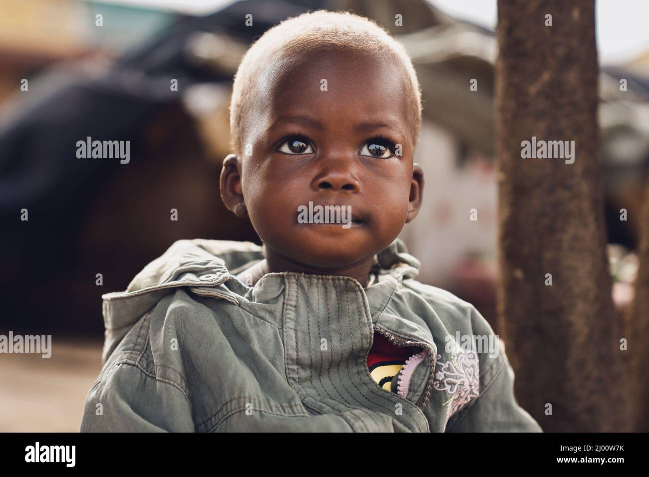 Ritratto di un bambino piccolo con occhi grandi e una giacca jean in Uganda. Foto Stock
