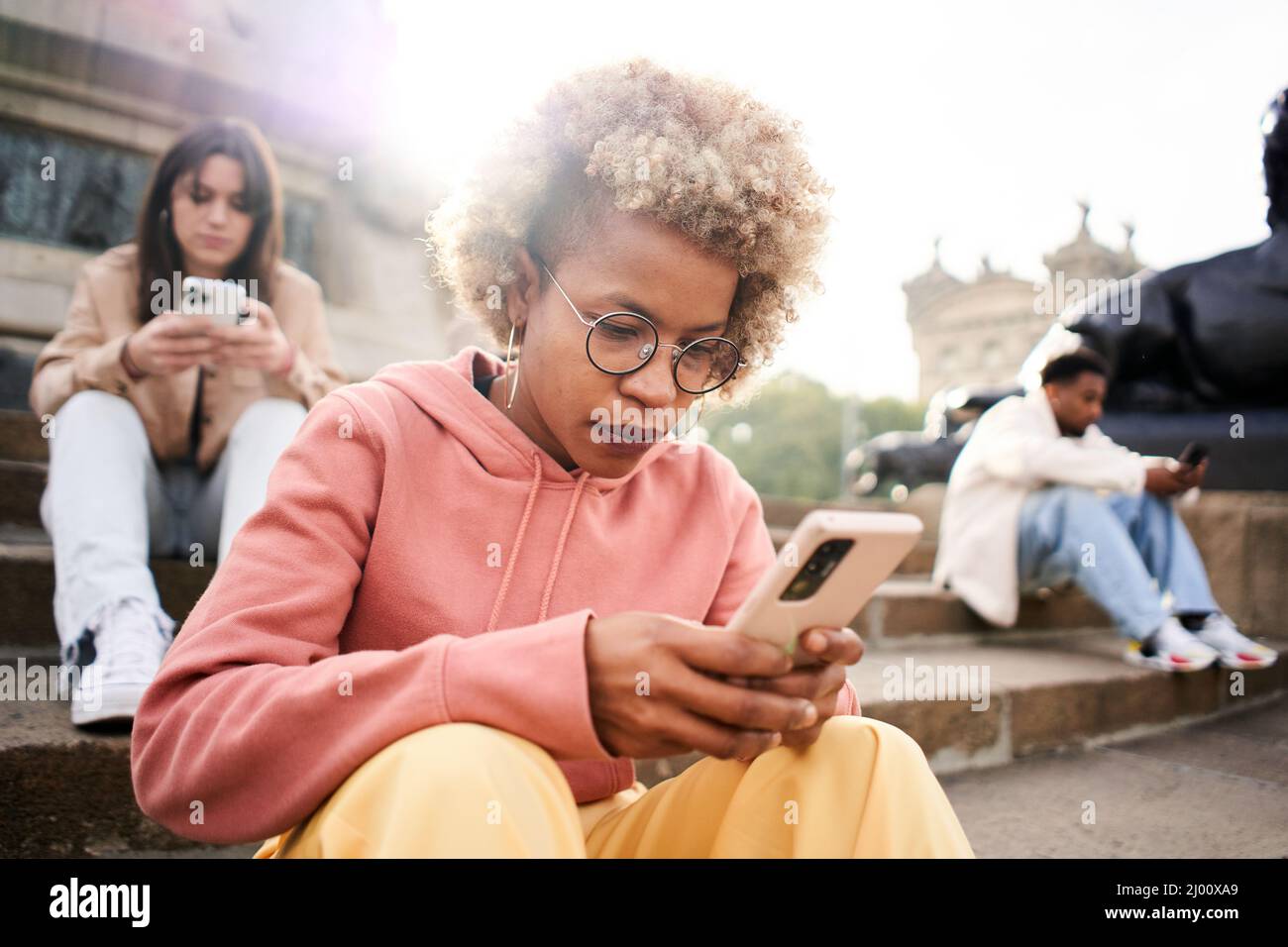 Gruppo di persone che si ignorano l'un l'altro utilizzando il telefono con faccia seria. Latina donna focalizzata sul loro mobile Foto Stock