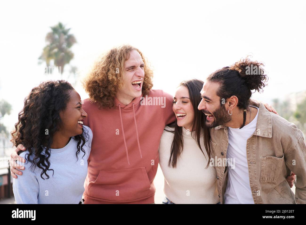 Sorridendo amici ridendo e divertendosi insieme. All'aperto. Buon gruppo di giovani multietnici che si abbraccia insieme. Foto Stock