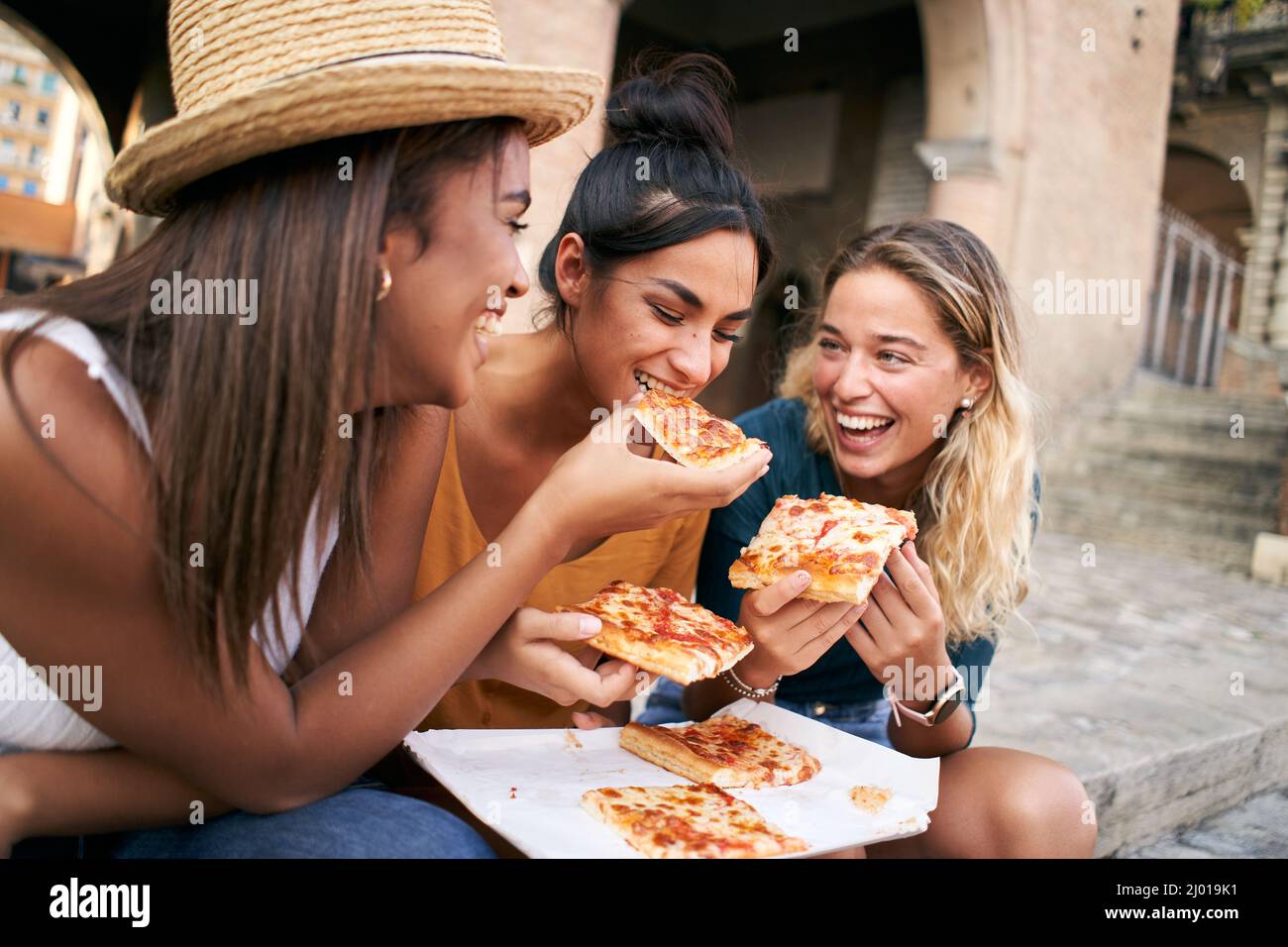 Divertente gruppo di tre ragazze che mangiano pizza in città. Giovane turista femmina divertirsi nelle vacanze estive Foto Stock