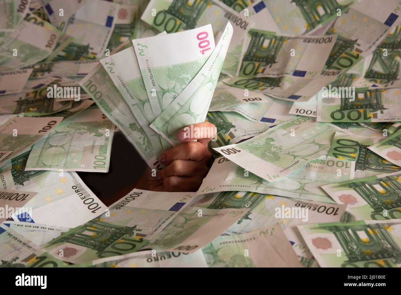 mano con le banconote in euro sale da una montagna di soldi Foto Stock
